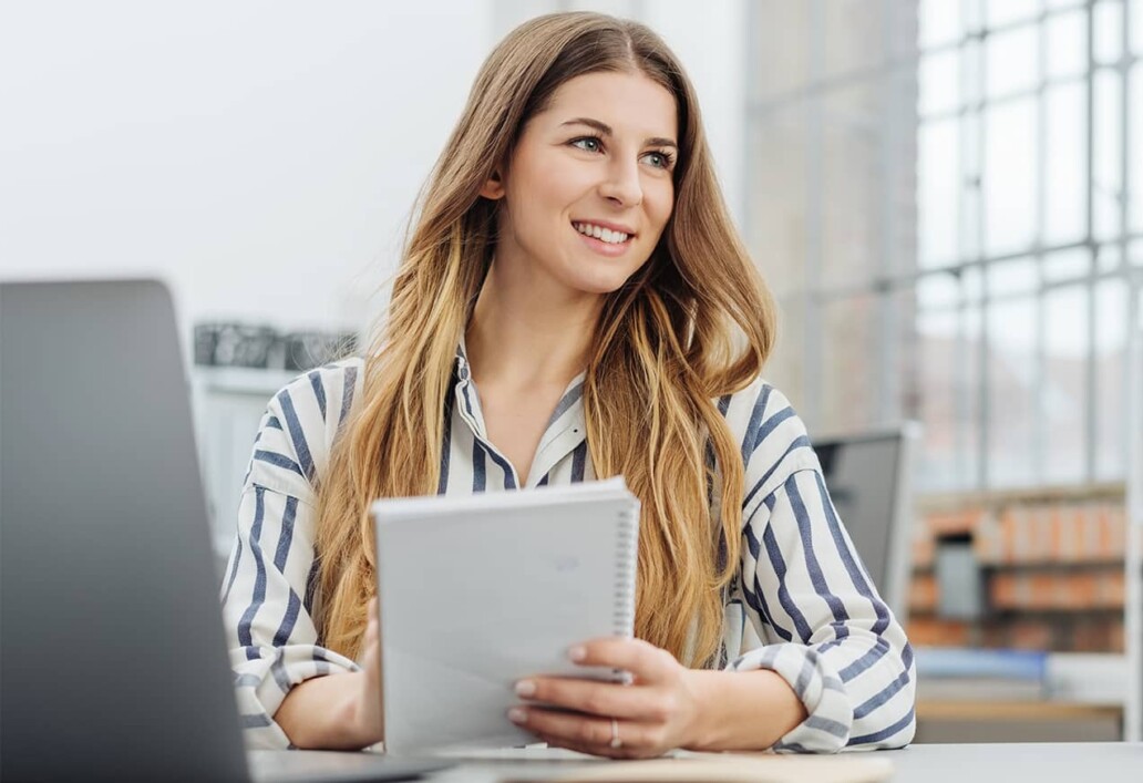 Young smiling woman holding notepad in office